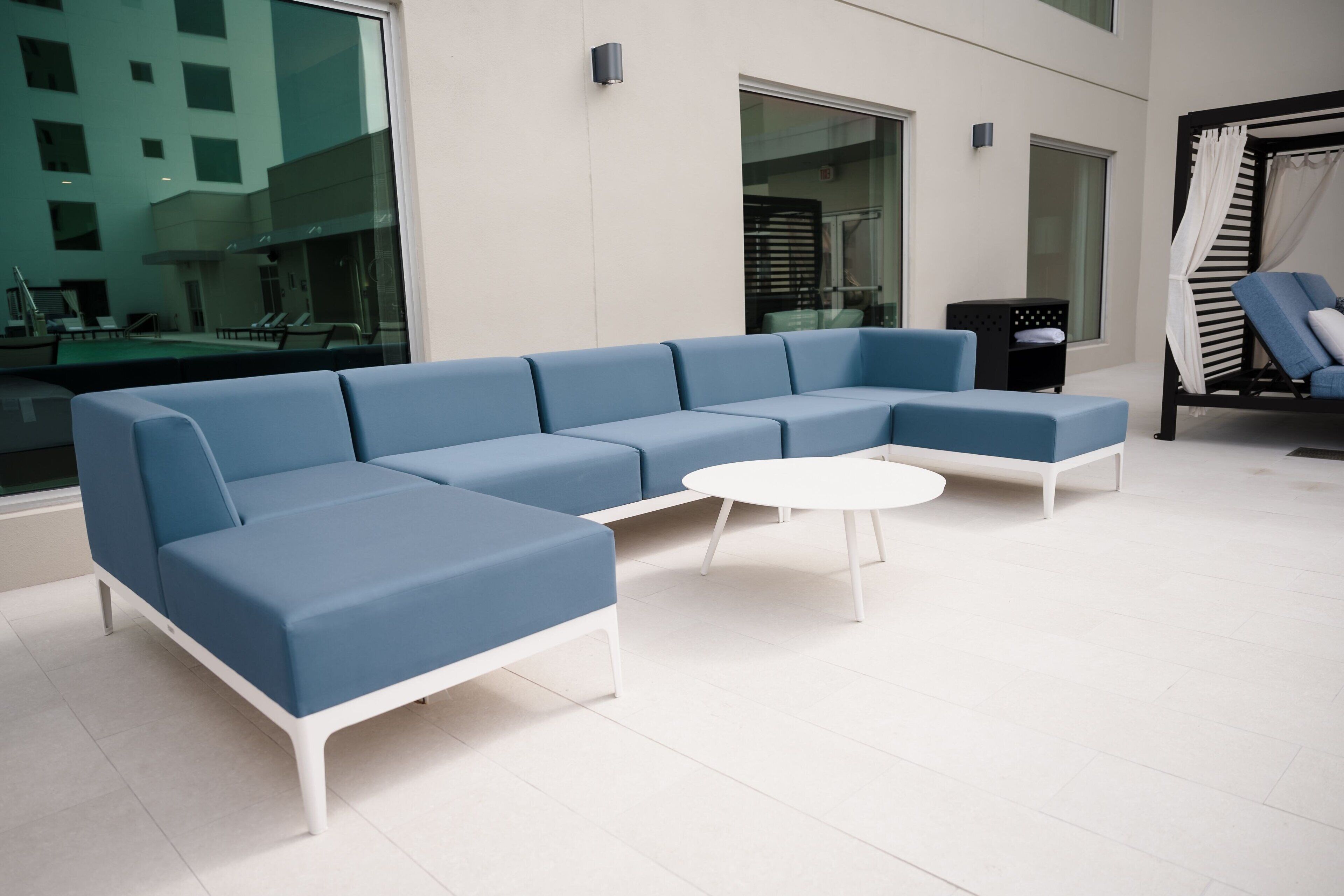 Ein moderner Lounge-Bereich mit einem blauen Ecksofa, einem weißen Couchtisch und einer schwarzen Ablage.