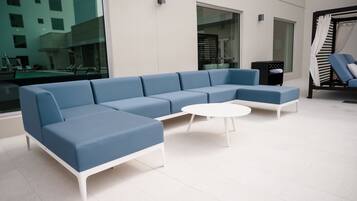 Ein moderner Lounge-Bereich mit einem blauen Ecksofa, einem weißen Couchtisch und einer schwarzen Ablage.