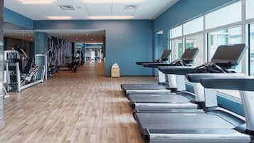 Un gimnasio moderno con cintas de correr, bicicletas estáticas y máquinas de pesas.