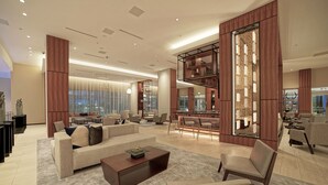 A spacious hotel lobby with a modern design, featuring a large seating area, a dining space, and a decorative wall with shelves. - AC Hotel by Marriott Fort Lauderdale Airport (Dania Beach)