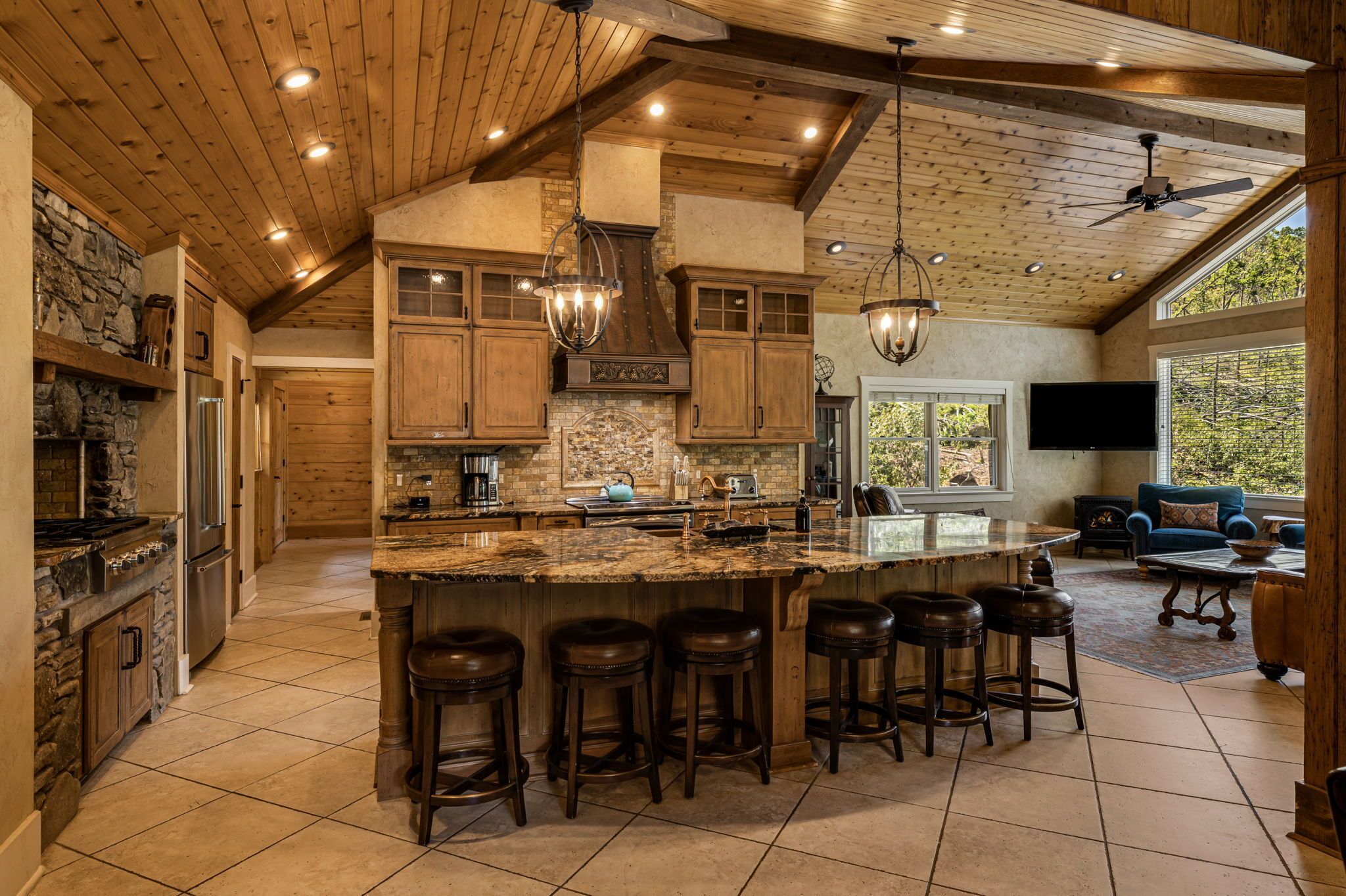 A spacious kitchen with a large island, wooden cabinets, and a stone backsplash.