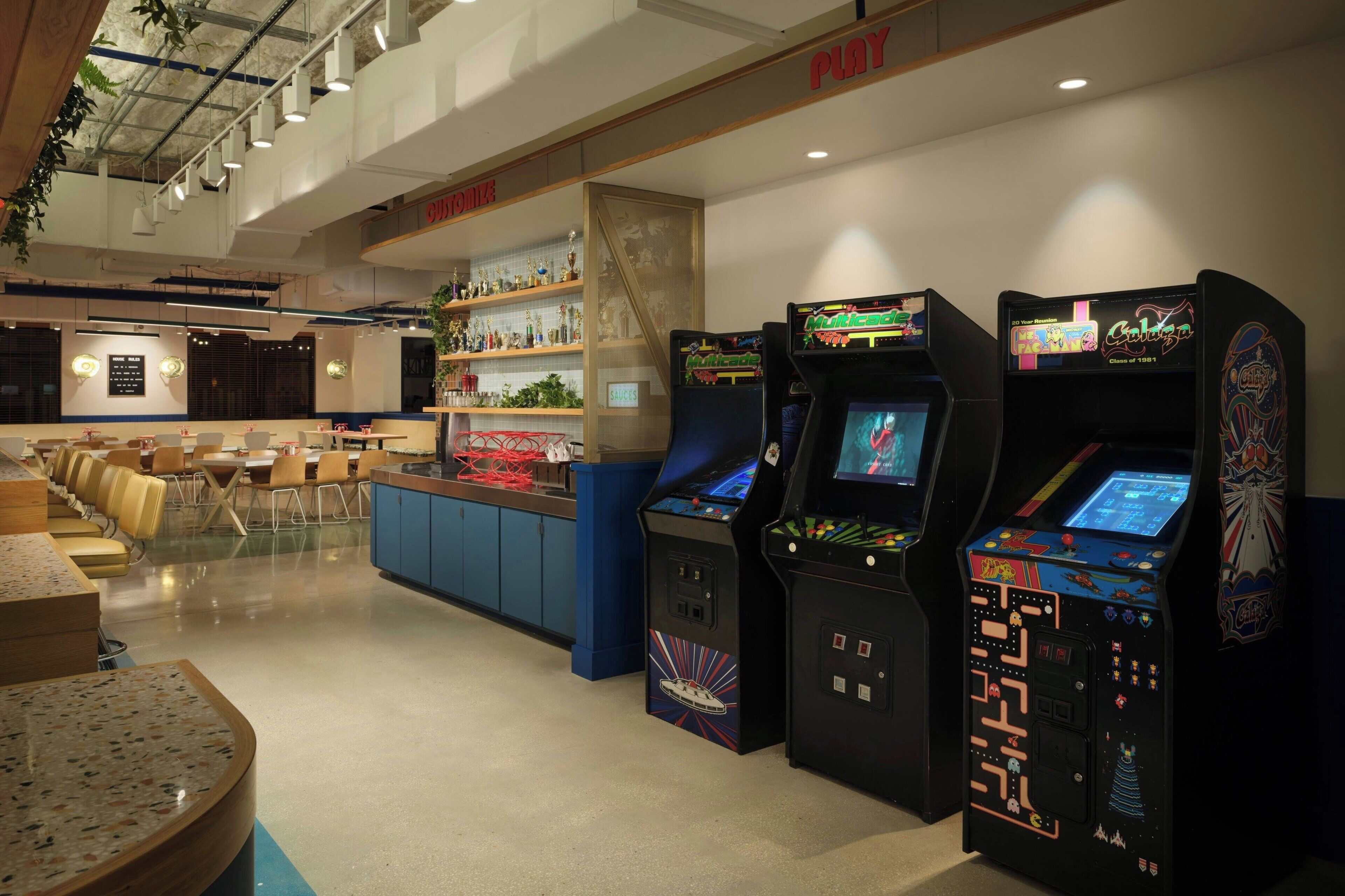 A gaming arcade with multiple arcade machines, a bar area, and seating.