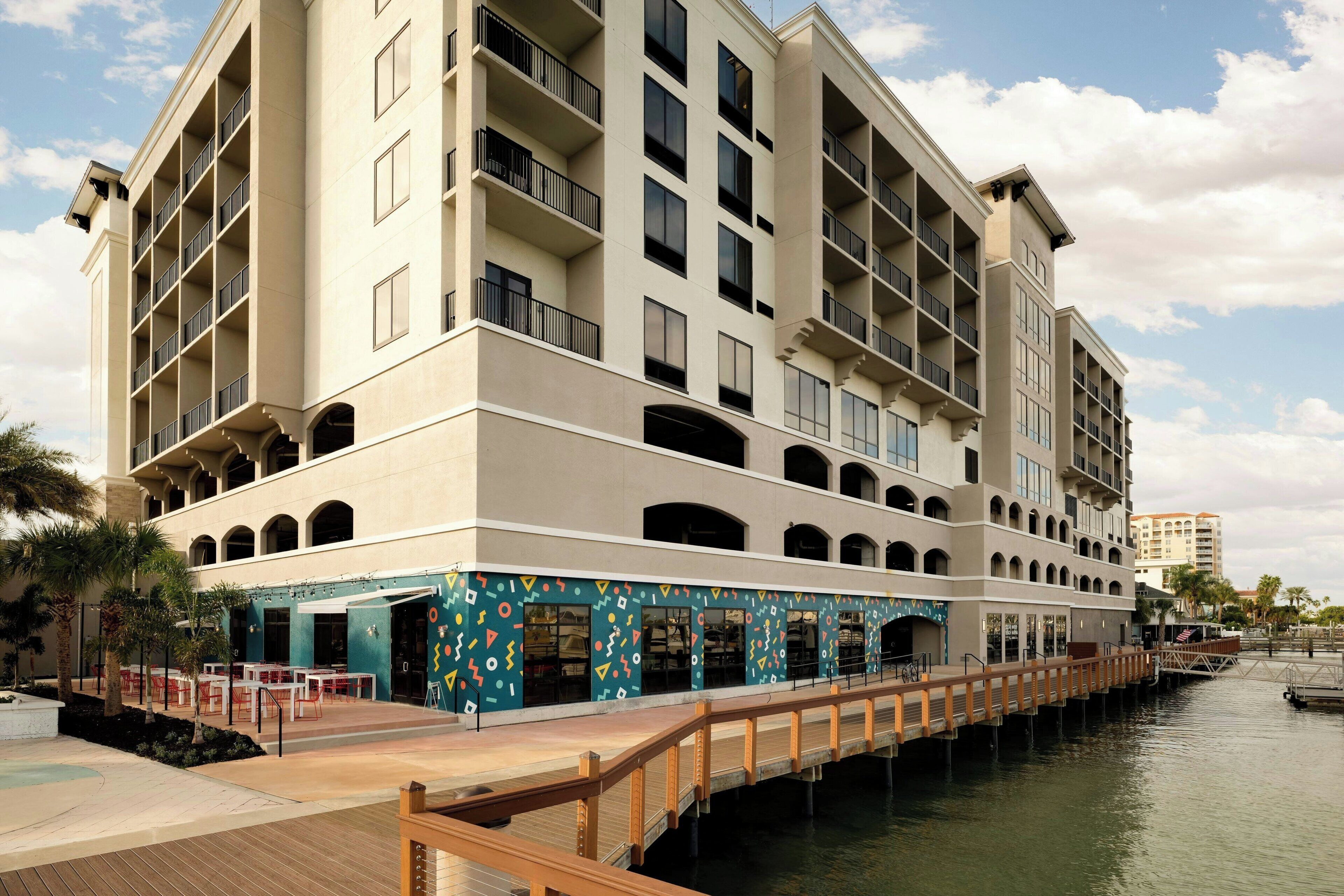 A multi-story hotel with balconies, a waterfront patio, and a covered outdoor seating area.