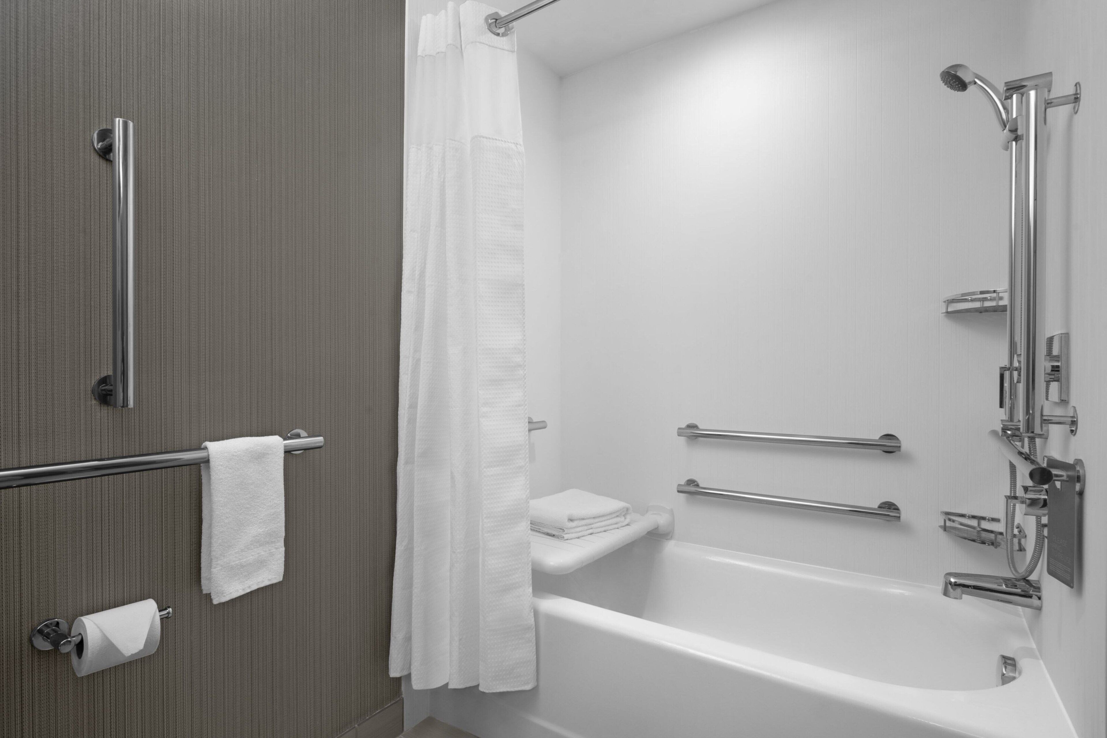 Ein modernes Badezimmer mit Badewanne, Dusche und Haltegriffen.