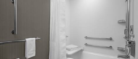 Ein modernes Badezimmer mit Badewanne, Dusche und Haltegriffen.