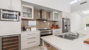 Eine moderne Küche mit Edelstahlgeräten, weißen Schränken und einem großen Fenster, das für natürliches Licht sorgt.