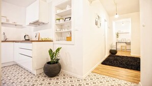 A modern kitchen with white cabinets, a black rug, and a potted plant. -  Batchae, Two Bedroom Flat near Bačvice Beach (Split)