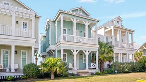 Eine Reihe von Häusern im Küstenstil mit Balkonen, einem Rasen und Palmen.