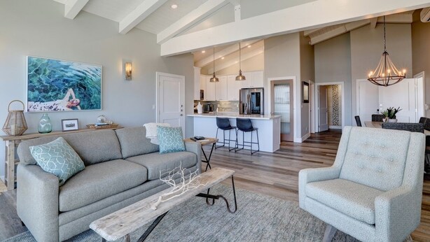 A spacious living area with a sofa, armchair, and a coffee table. A kitchen is visible in the background with a bar area. - Ocean front with Morro Rock views:  2Bdrm Condo at Salty Sister (Morro Bay)