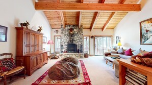 Una sala de estar acogedora con chimenea de piedra, vigas de madera, un sofá, un banco y una estantería.