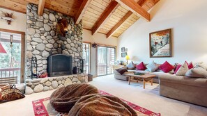 A cozy living room with a stone fireplace, wooden beams, a sofa set, and a large window. - Val DIsere 9 Spacious and Walk to The Village, Washer Dryer, Gas Grill, Master Suites and More by RedAwning (Mammoth Lakes)
