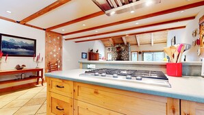 Una cocina con una estufa de gas grande, armarios de madera y una pared de piedra.