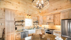 Een moderne keuken met houten kastjes, roestvrijstalen apparatuur en een centraal eiland met een koperen kom.