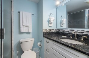 Ein Badezimmer mit Toilette, zwei Waschbecken mit schwarzer Arbeitsplatte und einem Spiegel über dem Waschbecken.