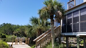 A wooden deck leading to a house with a large window overlooking a body of water. - Big Canal-front house, kayaks, canoes, game room, fish right from the dock. (Crawfordville)