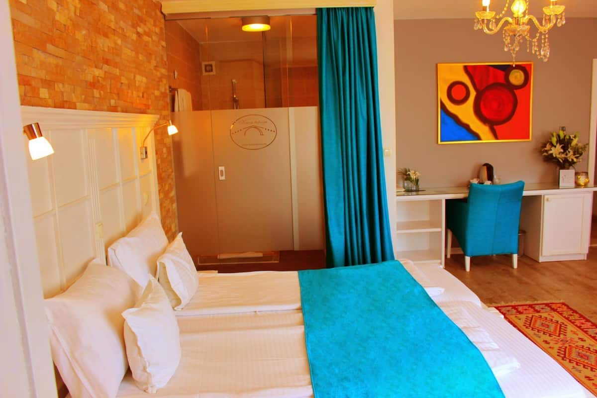 Une chambre d’hôtel avec un lit, un bureau, une chaise, une douche et un tableau au mur.