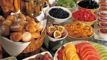 Un bufé con diversas opciones de comida, incluyendo frutas, verduras y panes.