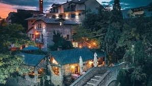 A historic building with a prominent tower, stone bridges, and lush greenery.