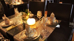 A dining table set with plates, napkins, and glassware, with chairs around it.