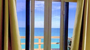 Una stanza con una grande finestra che si affaccia su una spiaggia.