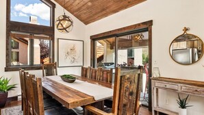 A dining area with a wooden table and chairs, a large window, and a mirror on the wall. - NEW LISTING | 3BR Townhouse with AC, Pool, Golf, Tennis (Avon)