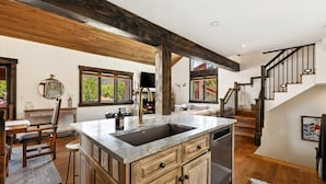A kitchen with a large island, wooden beams, a dishwasher, and a staircase leading to another level. - NEW LISTING | 3BR Townhouse with AC, Pool, Golf, Tennis (Avon)