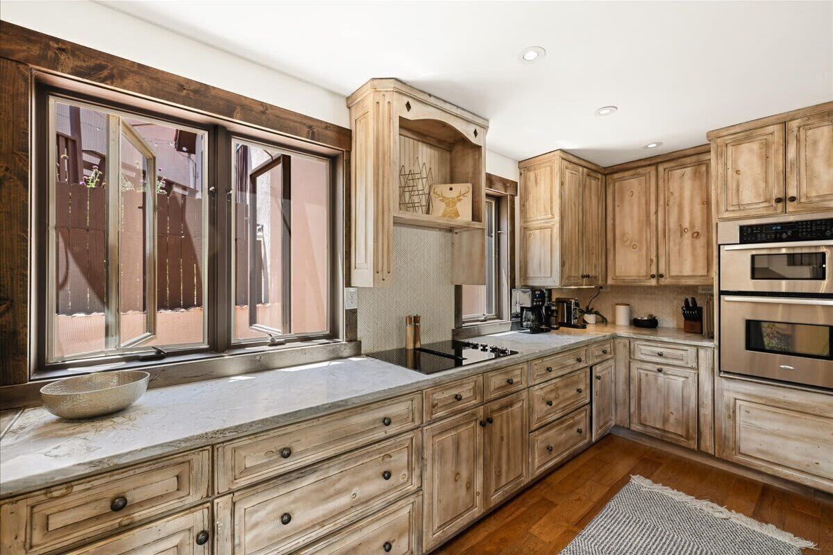 Una cocina con armarios de madera, un ventanal grande y una estufa empotrada.