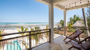 Ein Balkon mit Blick auf Strand und Meer, Holzliegen und Lichterketten.