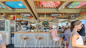 A bar with stools, a counter, and various bottles and glasses. - 2303 Seacrest - 2 Oceanfront Pools, Beach Bar, & Steps to the Beach! (Hilton Head Island)