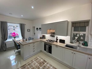 Une cuisine moderne avec des meubles gris, un îlot central et une fenêtre avec des rideaux.