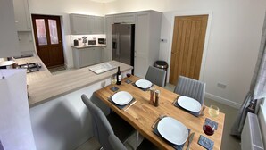 Een moderne keuken met een centraal eiland, inbouwapparatuur en een eethoek met een houten tafel gedekt voor vier personen.