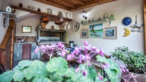 Una cocina rústica con vigas de madera, un horno de ladrillo y varios utensilios de cocina en estantes.
