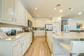 A kitchen with white cabinets, a central island, a microwave, a refrigerator, and a sink.
