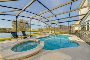 A covered outdoor swimming pool with lounge chairs and a view of a lake.