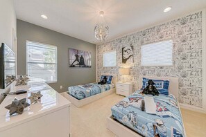 Une chambre avec deux lits, un bureau et un lustre.