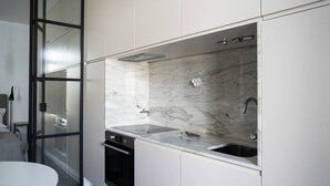 A modern kitchen with a built-in oven, a sink, and a marble backsplash.