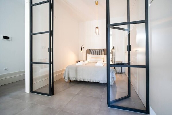 A modern bedroom with a bed, bedside tables, and a hanging light fixture.