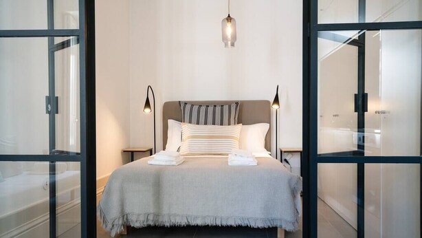 A modern bedroom with a large bed, two bedside lamps, and a hanging light fixture.
