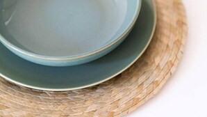 A blue ceramic bowl on a woven mat.