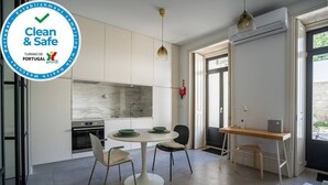 A modern kitchen with white cabinets, a marble backsplash, and a dining area with a round table and chairs.
