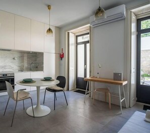 A modern kitchen with white cabinets, a marble backsplash, and a dining area with a round table and chairs.