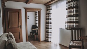 A cozy living room with a sofa, a wooden door, a dining table, and a chair. - Landhaus Andrea (Saalbach-Hinterglemm)