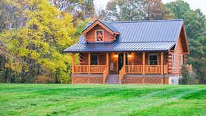 A log cabin with a metal roof, wooden porch, and a small window.