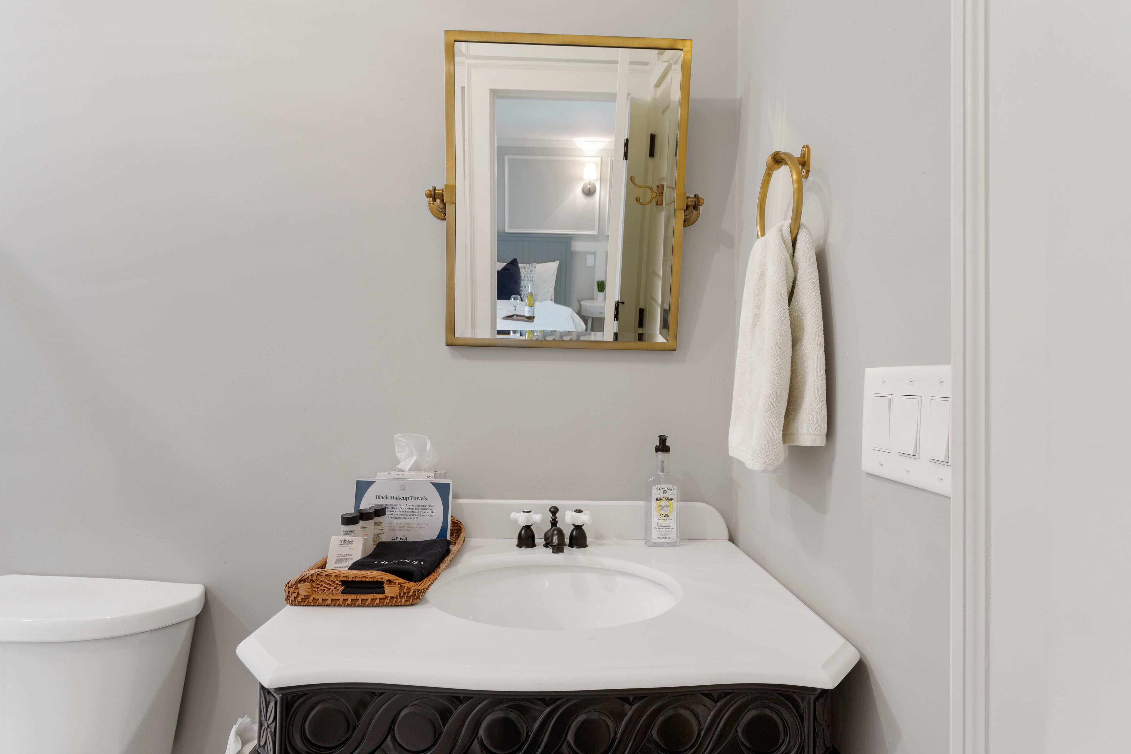 A bathroom with a white sink, a mirror with a gold frame, and a towel rack.