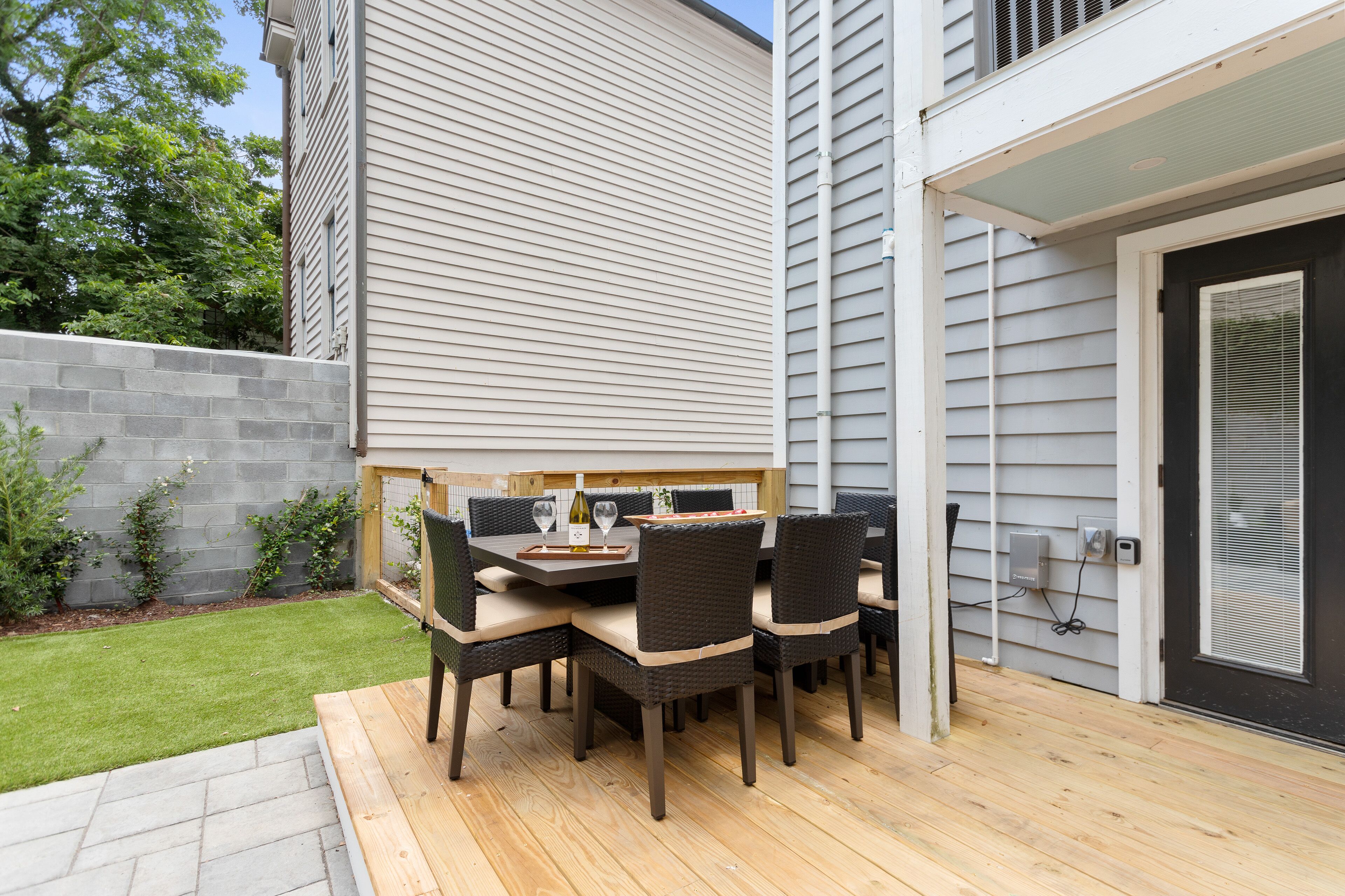 Patio esterno con tavolo e sedie, un molo di legno e un muro in mattoni.