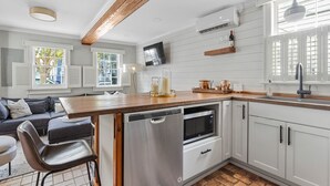 A modern kitchen with white cabinetry, a wooden countertop, a built-in dishwasher, and a microwave. - Only 3 Blocks from King | Backyard! | The Felix (Charleston)