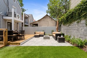 A backyard patio with outdoor furniture, a wooden deck, and a stone-tiled patio. - Only 3 Blocks from King | Backyard! | The Felix (Charleston)