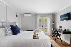 A hotel room with a bed, a desk, a TV, and a view of the outdoors. - Only 3 Blocks from King | Backyard! | The Felix (Charleston)