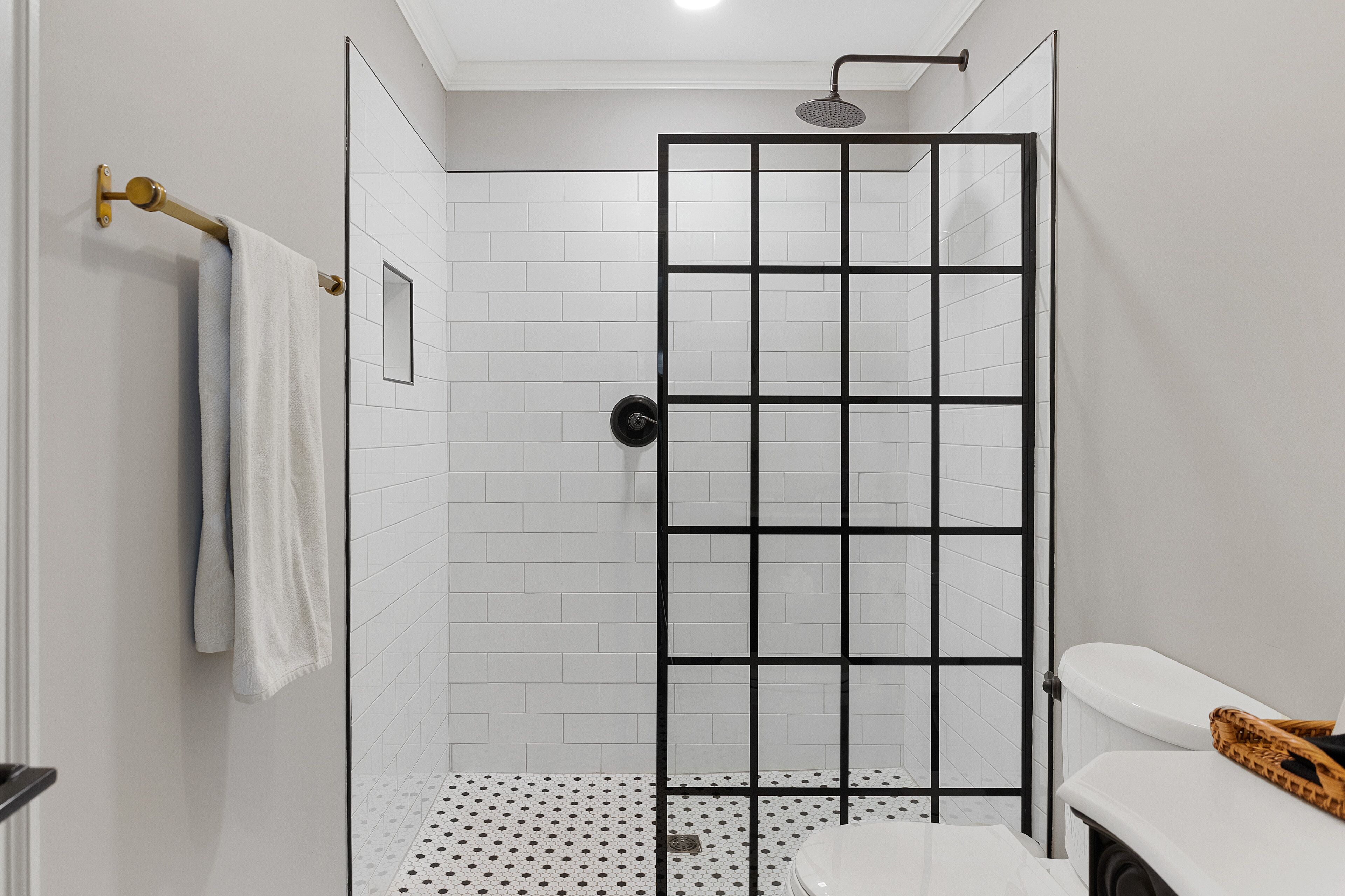 A modern bathroom with a shower enclosure, a toilet, and a towel rack.
