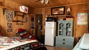 Ein gemütliches Zimmer mit einem Bett, einem Kühlschrank, einer Mikrowelle und einem Schrank.